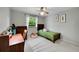 Bright bedroom with a wood-frame bed, ceiling fan, desk, and sunny window with green outdoor views at 7439 S Depew St, Littleton, CO 80128