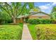 Charming brick home featuring a mature tree, manicured lawn, and welcoming walkway at 7439 S Depew St, Littleton, CO 80128