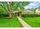 Charming brick home featuring a mature tree, manicured lawn, and welcoming walkway at 7439 S Depew St, Littleton, CO 80128