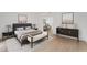 Beautiful bedroom with a large bed, bench, hardwood floors, and artwork displayed above a dark wood console table at 2111 E Alameda Ave, Denver, CO 80209