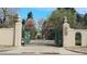 View of the East Alameda entry gate with wrought iron fencing and gate surrounded by mature trees at 2111 E Alameda Ave, Denver, CO 80209