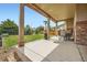 Covered back porch featuring a dining area, stone pillars, and backyard view at 350 N Langdale Ct, Aurora, CO 80018