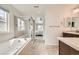 Bright bathroom showcasing a soaking tub, glass enclosed shower, and neutral tiling at 350 N Langdale Ct, Aurora, CO 80018