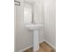 Clean powder room with pedestal sink, modern mirror, and wood-look flooring at 21134 E 63Rd Dr, Aurora, CO 80019