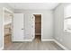 This bedroom features gray walls, wood-look floors, an open closet, and two open doorways at 2520 E 127Th Ave, Thornton, CO 80241