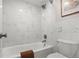 A bathroom featuring white marble-style tile, a shower-over-tub, toilet, and framed artwork at 4570 E Yale Ave # 507, Denver, CO 80222