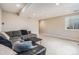 Comfortable basement area featuring a large sectional, neutral carpet, and ample lighting from the window and recessed lights at 9799 Falcon Ln, Littleton, CO 80125