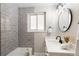 Well lit bathroom with a white vanity, an oval mirror, and a tub with gray subway tile at 2570 Bell Ct, Lakewood, CO 80215