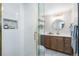 Bathroom with a glass shower, wood vanity, gold hardware, and marble tile flooring at 2570 Bell Ct, Lakewood, CO 80215