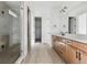 Modern bathroom with dual sinks, wood cabinets, sleek lighting, and a glass-enclosed shower at 25224 E Warren Pl, Aurora, CO 80018
