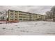 Tan three-story apartment building with snow-covered lawn at 9335 E Center Ave # 4B, Denver, CO 80247