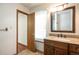 Bright bathroom showcasing a wood vanity, granite countertop, and view to an opened door and window at 7732 Xavier Ct, Westminster, CO 80030