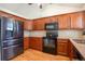 Well-lit kitchen featuring dark cabinets, stone countertops, and modern black appliances at 7732 Xavier Ct, Westminster, CO 80030