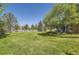 Large, grassy backyard surrounded by a white fence and mature trees providing a private outdoor space at 10529 Dacre Pl, Lone Tree, CO 80124