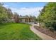 Lush backyard with manicured lawn, mature trees, and stone walkway to back of house at 395 Zephyr St, Lakewood, CO 80226
