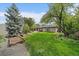 Lush green backyard featuring garden beds and mature trees, perfect for outdoor relaxation and gardening at 395 Zephyr St, Lakewood, CO 80226