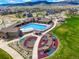 Aerial view of community pool, playground and clubhouse, with walking path, open grass, and mountain views at 19593 W 93Rd Ln # E, Arvada, CO 80007