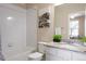 Well-lit bathroom featuring a granite countertop, tiled shower with tub, and decorative mountain scene artwork at 19593 W 93Rd Ln # E, Arvada, CO 80007