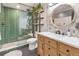 Modern bathroom with a glass enclosed shower with emerald green tiling, wood vanity, round mirror and grey floors at 1203 24Th St, Denver, CO 80205
