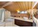 A well-lit bathroom with a corner tub, a vanity with a vessel sink, a brick accent wall, and a wood ceiling with a skylight at 1203 24Th St, Denver, CO 80205