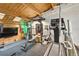 Home gym with black rubber flooring, weights, exercise machines, a fan, a TV, brick accents and a wood plank ceiling at 1203 24Th St, Denver, CO 80205