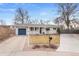 Inviting single-story home featuring a well-manicured lawn, blue garage door and charming front porch at 1359 Chambers Rd, Aurora, CO 80011