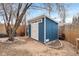 Exterior shot of the well-maintained blue and white storage shed on a gravel base with surrounding landscaping at 1359 Chambers Rd, Aurora, CO 80011