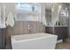Clean bathroom featuring modern soaking tub, neutral tile, and chrome hardware under large picture window at 2223 W 34Th Ave, Denver, CO 80211