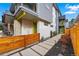 Modern home featuring a stone walkway, a yellow door, privacy fence, and metal balcony at 2223 W 34Th Ave, Denver, CO 80211