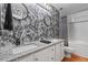 Stylish bathroom with dual sinks, granite countertops, and striking black-and-white wallpaper at 1555 California St # 414, Denver, CO 80202