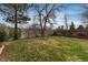 Spacious backyard with green grass, a picnic table, mature trees, and a wood pile, great for relaxing at 7676 S Olive Cir, Centennial, CO 80112