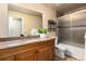 Bright bathroom featuring granite counters, wood cabinets, and a tiled shower-tub combination at 7676 S Olive Cir, Centennial, CO 80112