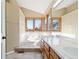 Bright bathroom featuring a tub under windows and double vanity with tile countertop at 11932 W 56Th Cir, Arvada, CO 80002