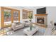 Cozy living room with a brick fireplace, plush seating, wood floors, and access to the outdoor deck at 11932 W 56Th Cir, Arvada, CO 80002