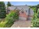 Aerial view of a brick home featuring a tile roof, three-car garage, and a paved driveway at 51 Falcon Hills Dr, Highlands Ranch, CO 80126