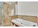 This updated bathroom features a large tub, glass enclosed shower, and earth tone tile at 51 Falcon Hills Dr, Highlands Ranch, CO 80126