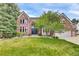 Charming two-story brick home with a well-manicured lawn, mature trees, and an attached two-car garage at 51 Falcon Hills Dr, Highlands Ranch, CO 80126