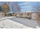 Spacious backyard with snow-covered lawn and covered patio at 4441 E Montana Pl, Denver, CO 80222