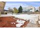 Spacious backyard with a lawn, fencing, patio, and snow, providing a versatile outdoor space for various activities at 5800 W Warren Ave, Denver, CO 80227