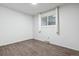 Bright bedroom featuring modern wood floors, and a sunlit window with white trim and matching curtains at 5800 W Warren Ave, Denver, CO 80227