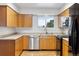 Charming kitchen featuring wooden cabinets, stainless steel dishwasher, and a window view at 5800 W Warren Ave, Denver, CO 80227