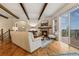 Bright living room featuring hardwood floors, beamed ceilings, and a stone fireplace with deck access at 2891 Waterfront Dr, Monument, CO 80132