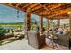 Covered patio featuring stone columns, string lights, comfortable seating and lake views at 2891 Waterfront Dr, Monument, CO 80132