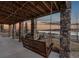 Outdoor porch with stone pillars, wood beams, and swing overlooking the waterfront at 2891 Waterfront Dr, Monument, CO 80132