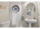 Cozy powder room features a round mirror, pedestal sink, and a wall-mounted decorative shelf at 2550 Gold Creek Dr, Elizabeth, CO 80107