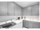 Well-organized laundry room with modern gray cabinets, sink, and newer model washer and dryer at 10524 Eby Cir, Lone Tree, CO 80124