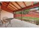 Covered back porch with a chair, table and an opening into the backyard space with a wooden fence at 6293 Ponderosa Way, Parker, CO 80134