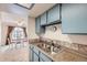 Cozy kitchen featuring blue cabinets and stainless steel sink, seamlessly flowing into a bright dining area at 6009 Yarrow St # B, Arvada, CO 80004