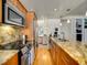 Galley kitchen with wood cabinets, granite counters, stainless steel appliances, and hardwood floors at 1011 N Pennsylvania St # H, Denver, CO 80203