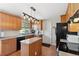 Galley kitchen featuring wood cabinets, black appliances, an island, and granite countertops at 1853 S Zeno Way, Aurora, CO 80017